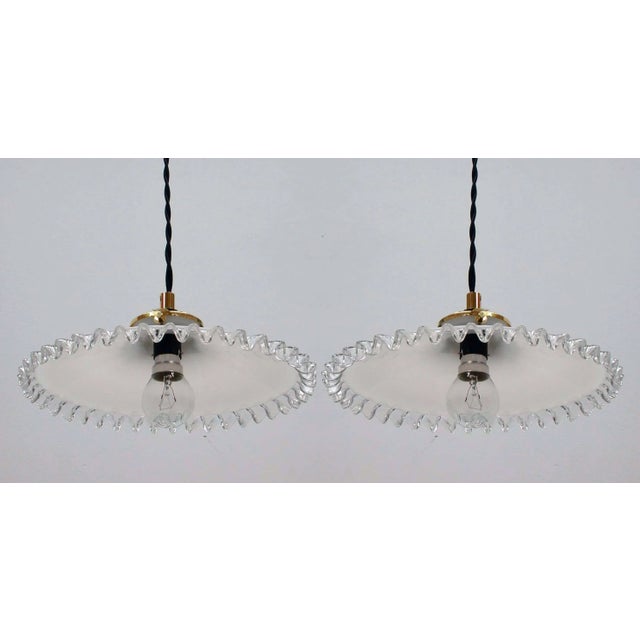 These pendant lights were made in France in the 1950s. The lamps have got white opaline pleated glass lampshades and brass...