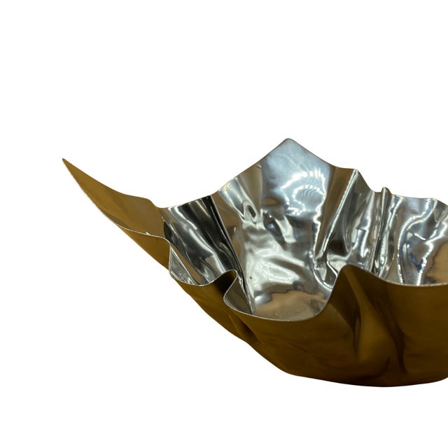 This striking vintage bowl is a sculptural study in movement and reflection, defined by its dramatic, crumpled form that...