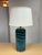 Design Plus Gallery presents an Oceanic Blue Table Lamp. The style is eclectic and has deep blue colors of teal and navy...