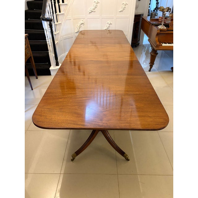 A substantial antique figured mahogany three-pillar extending dining table of classic rectangular form with softly rounded...