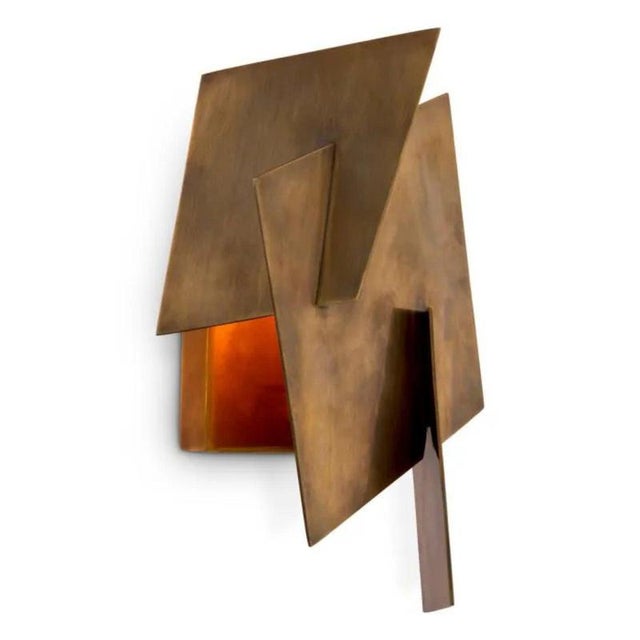 Pair of contemporary wall lamp featuring a vintage brass finish and a sculptural geometric metal design inspired by folded...