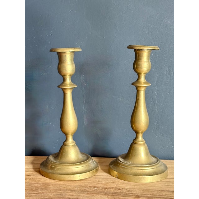 Pair of cast brass candlesticks, each with an urn-form socket and wide dished drip pan on a knopped baluster stem, rising...