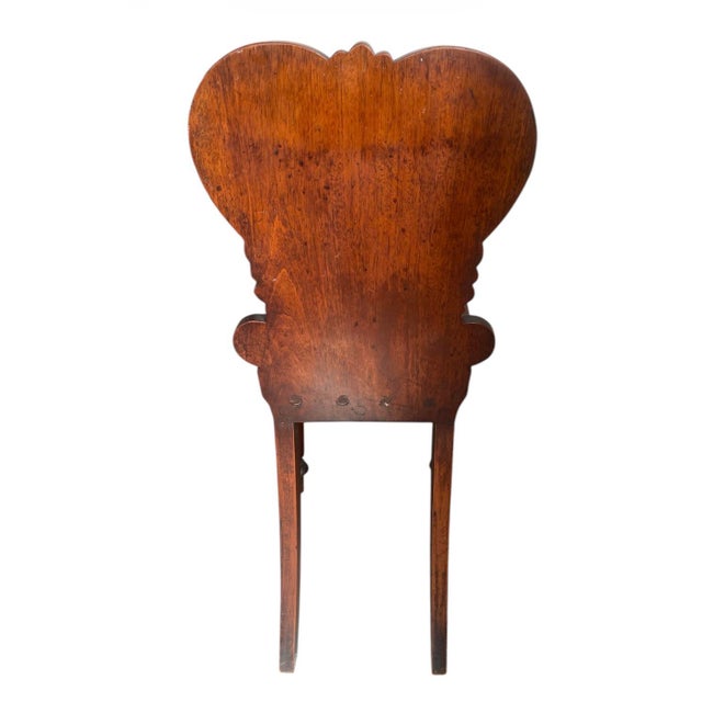 This striking antique hall chair is a beautiful example of classical influence and craftsmanship. Carved from a rich, warm...