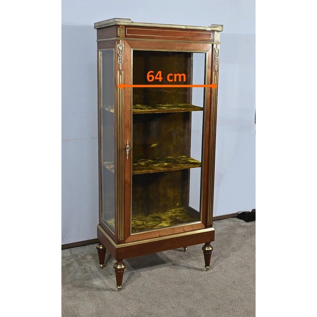 Small all-sided mahogany display case decorated with brass moldings. Indeed, its sides and the door frame are decorated...