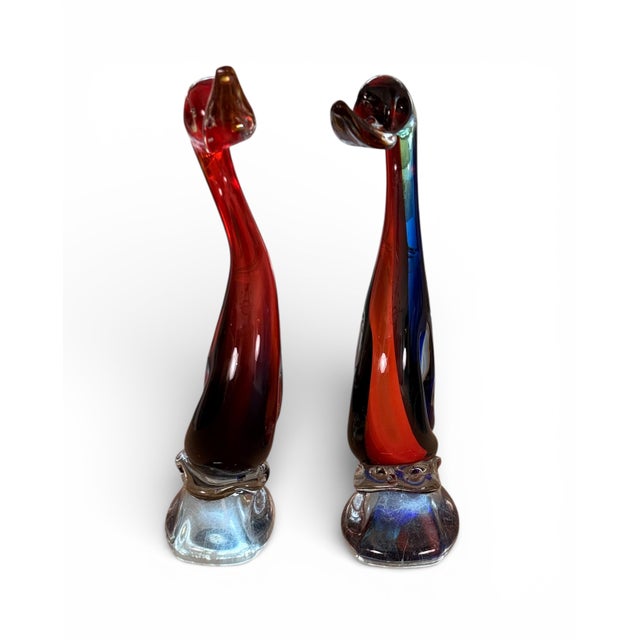 This striking pair of hand-blown, cased art glass sculptures features elegant swan forms rendered in rich layered tones of...