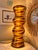A striking sculptural table lamp featuring a dramatic, undulating hourglass silhouette and flowing ochre-gold stripes...