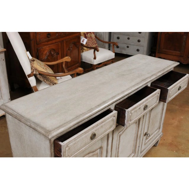 A Swedish painted wood sideboard from the late 19th century, with three drawers over three doors. Created in Sweden during...