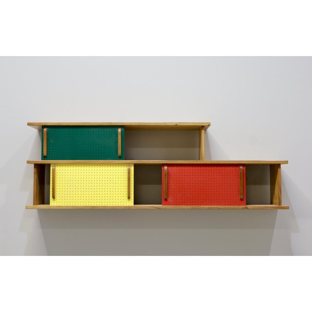 Wall-mounted bookcase by Charlotte Perriand, 1950s. Made in France, in solid wood and red, green, and yellow varnish. In...
