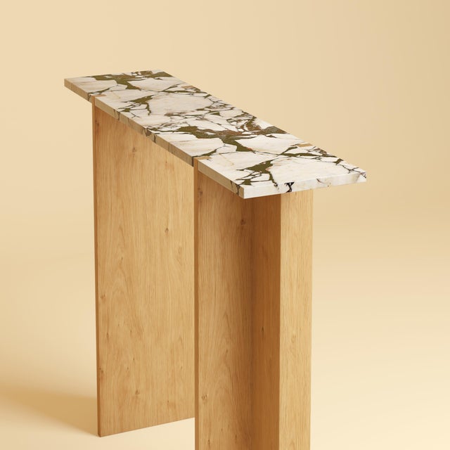The Maha is a Calacatta Viola marble and oak console table, a slim, upright table made to sit against a wall in which a...