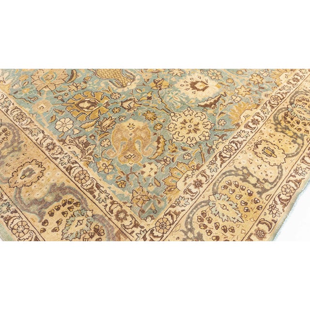A hand-knotted wool antique Persian Tabriz rug dating back to circa 1930. The main field is all over stylized in rich...