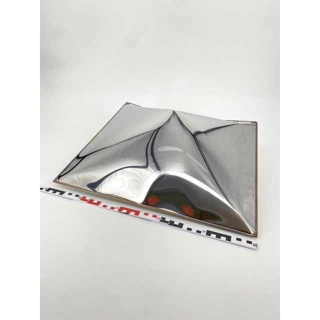 An art object * Sculpture in the shape of a pillow * Made of metal * Chrome-colored * Hydroforming: this technique...