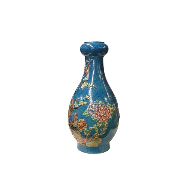 This elegant ceramic vase exudes a refined charm with its deep blue glaze and graceful, elongated shape. The vase features...