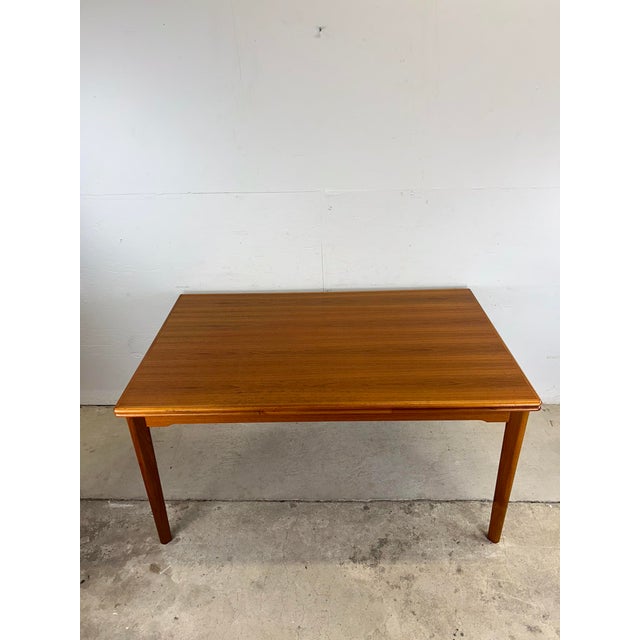 This Danish modern dining table features pressed wood construction, teak veneer with original finish, two draw leafs and...