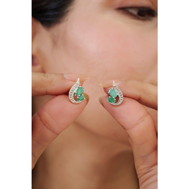 These elegant 1.85 carat emerald and diamond stud earrings are crafted in 925 sterling silver and feature a graceful leaf-...