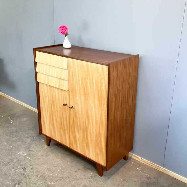 A striking highboard in typical 1960s design, featuring a beautiful contrast between the darker body and light fronts. The...