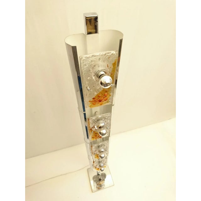 This floor lamp features a heavy chrome base with a total of eight lightbulbs. Four light bulbs sit behind the glass...