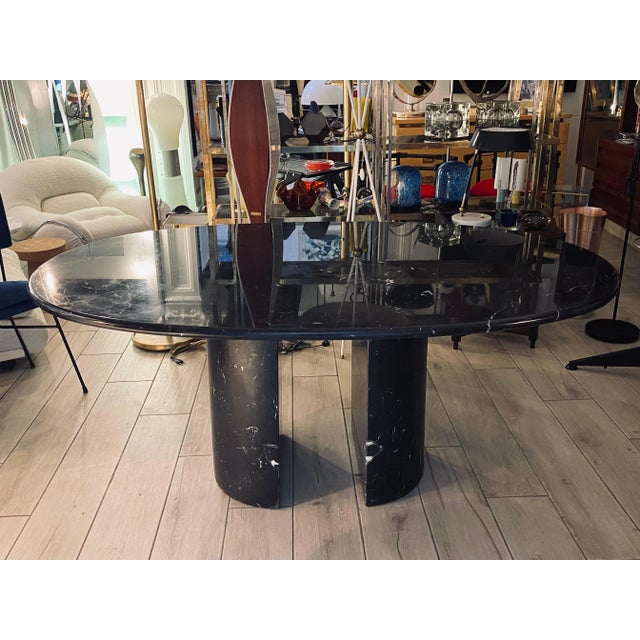 The majestic oval top in Dolmen marble, 3 cm thick, rests on two free semicircular bases made of the same material to...