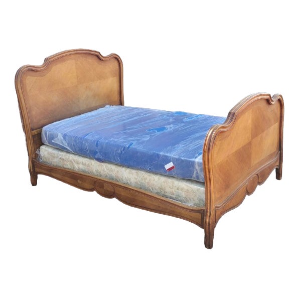 A striking antique French Provençal bed distinguished by its graceful serpentine form, hand-carved detailing, and...