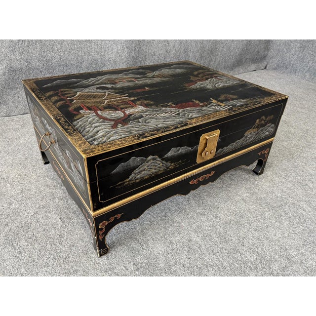 This Chinoiserie decorated cocktail table features a hand-painted scenic landscape with pagodas, figures, and mountains in...