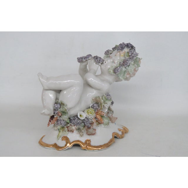 This charming Cherub Figurine is made of porcelain. This darling piece features an English Derby style cherub figure...