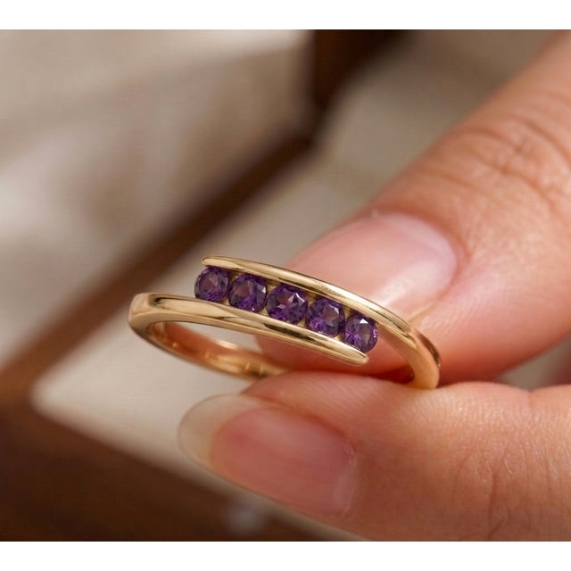 Indulge in a touch of modern royalty with this striking amethyst bypass ring. This contemporary piece features a sleek,...