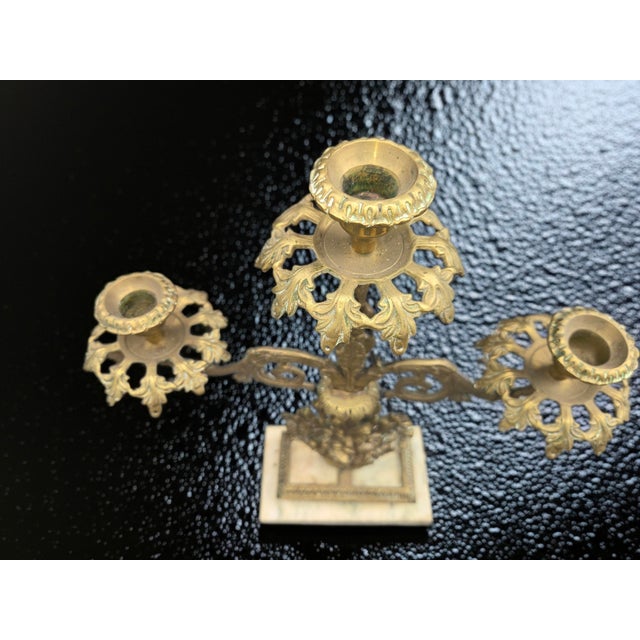 A beautiful antique brass girandole candelabra featuring an ornate basket-of-flowers motif set on a marble base. American...