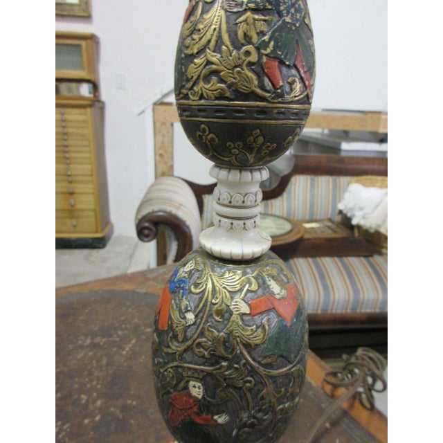A magnificent table lamp with a stacked column of painted and gilt elements decorated with figures in Renaissance costumes...