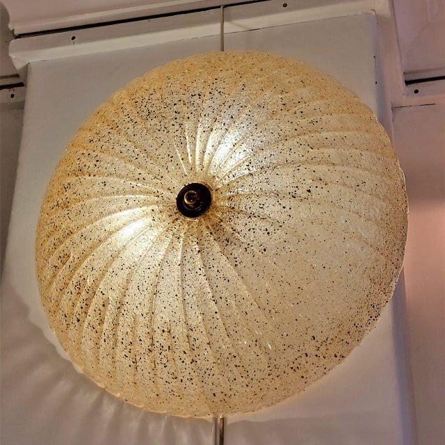 Semi-spherical wall sconce crafted from Murano glass with a fluted surface that curves towards the center, is slightly...