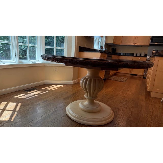 A beautifully crafted round dining table featuring a rich two-tone design that pairs a warm, dark-stained wood top with a...