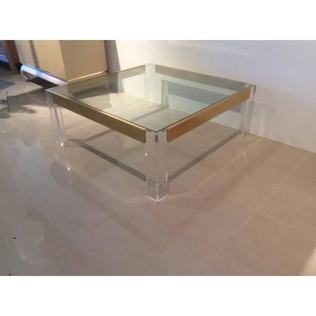 Lovely vintage Hollywood Regency, Lucite and brass coffee cocktail table in the manner of Charles Hollis Jones. The glass...