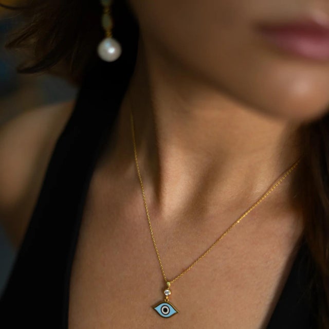 Add a touch of spiritual charm to your look with this Celestial Protection Light Blue Evil Eye Necklace. Crafted in...