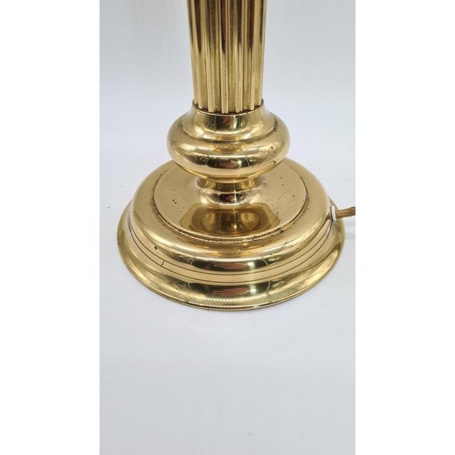 This retro-style table lamp combines a solid brass base with a mirror finish and a shade made of frosted amber glass with...