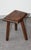 This handcrafted tripod stool in solid wood, with a brutalist design, has a sturdy hexagonal seat with rounded edges...