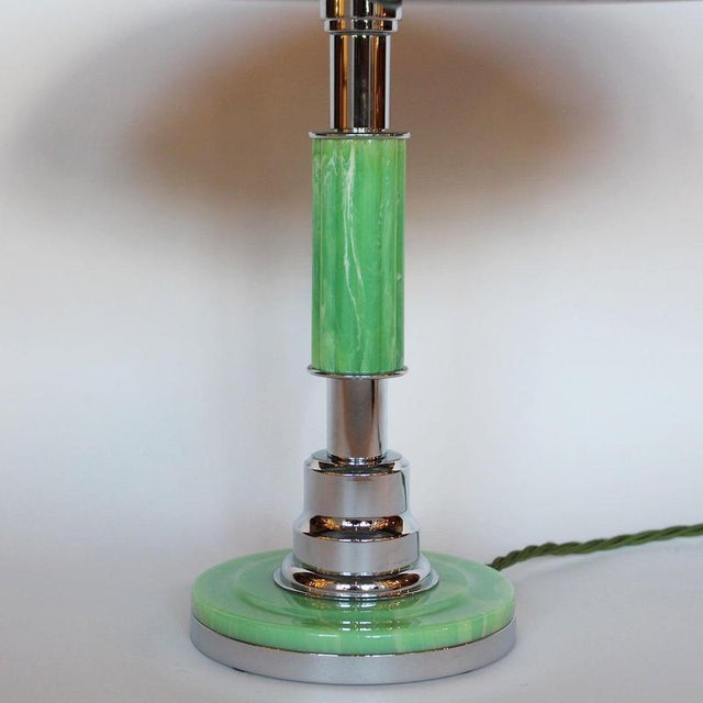An Art Deco table lamp with domed shade and metal finial. Reeded, mint green bakelite stem over a stepped metal and...