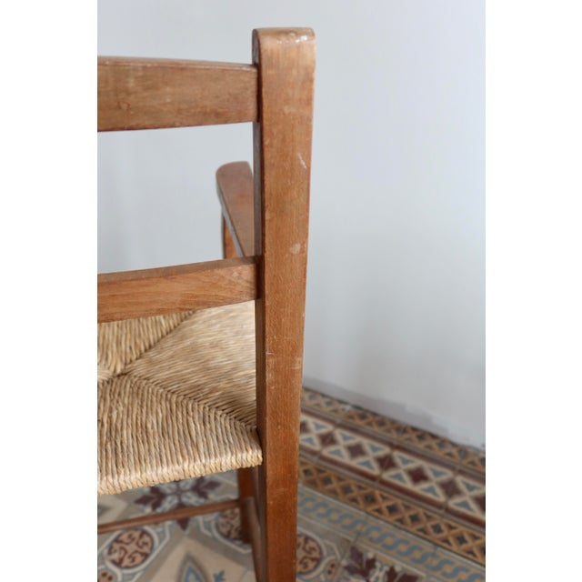 Antique solid wood high chair with armrests and a woven straw seat, featuring simple and authentic lines. Beautiful...