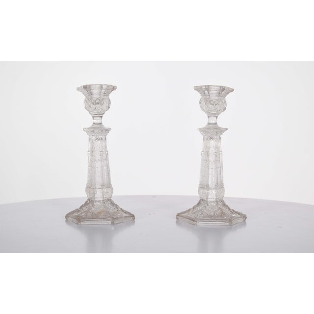 This elegant pair of glass candlesticks features intricate relief work, adding texture and dimension to their refined...