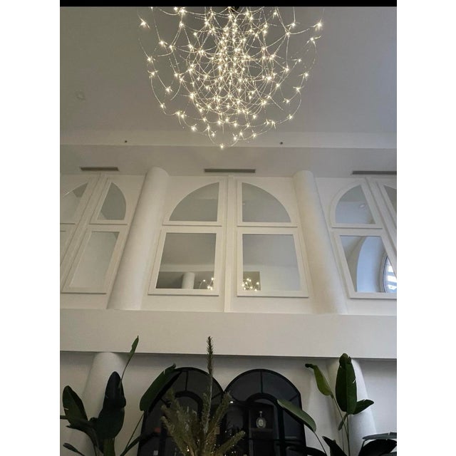 The Q2 chandelier by DDC showcases an elegant design featuring curved nickel rows, meticulously arranged to create a...