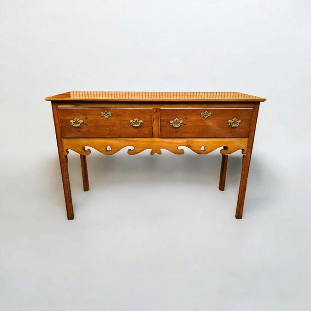 This Wright Table Company George III Style Yew Wood Two-Drawer Sideboard features warm golden hues that constitute the...