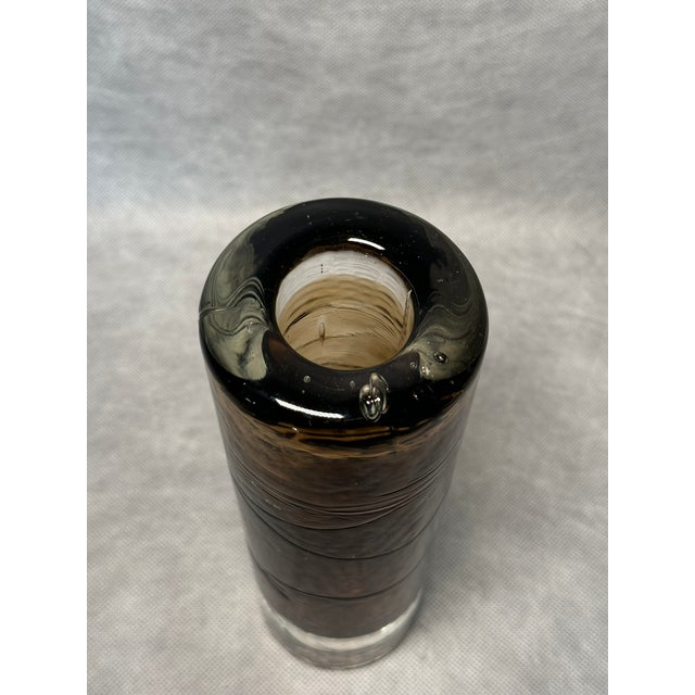 Cylindrical vase made of thick layered blown glass in transparent and brown tones. The clean minimalist form highlights...