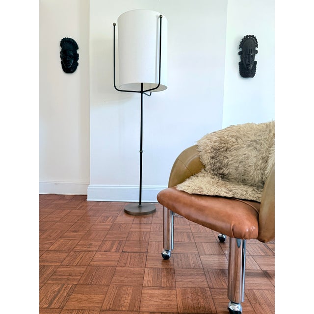 Contemporary Boise floor lamp by Arteriors featuring a slender bronze iron frame anchored by a substantial antique brass...