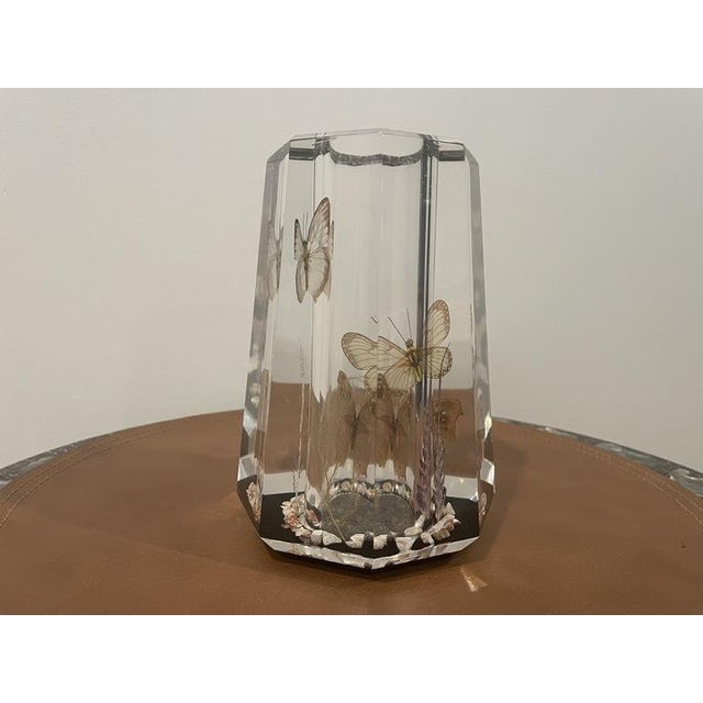 Decorative acrylic vase featuring butterflies and ornamental botanical elements encased within the clear body. The...