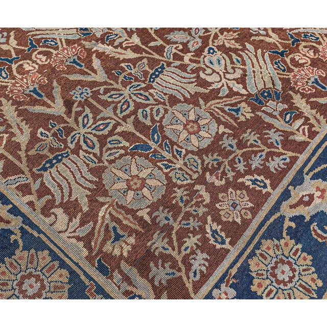 An early 20th century Indian antique rug, the cinnamon field with an allover trellis of flowering vines and flowerheads...