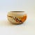 A vintage nemadji pottery bowl with a beautiful organic pattern of blue and orange swirls on a light off-white background....