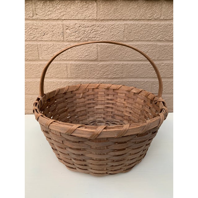 A beautifully woven early 20th century American splint oak basket with warm honeyed tones and a tightly constructed...