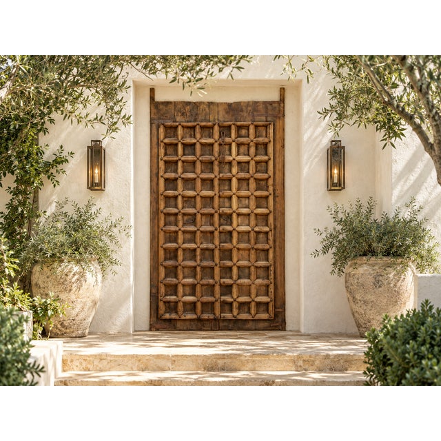 The carving is what stops you. A finely carved grid of raised square panels covers the front of each door, its oxidized...