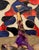 A gathering of loosely rendered figures fills this canvas in bursts of red and cobalt blue, set against the gold leaf...
