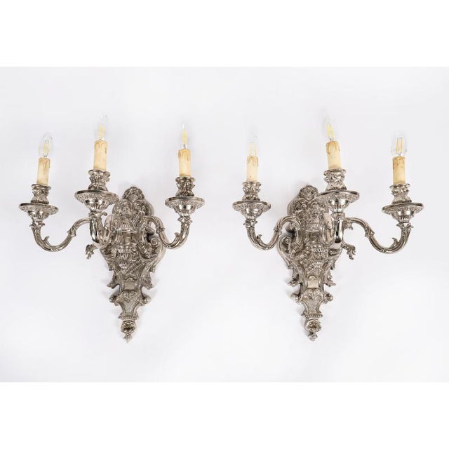 This is a fine antique set of four French Baroque revival silver-plated wall lights circa 1900. They feature shaped shield...
