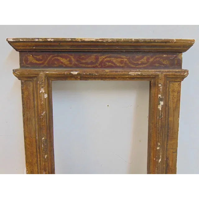 A beautifully aged 17th-century Italian gilt and polychrome frame featuring stepped architectural moldings and hand-...