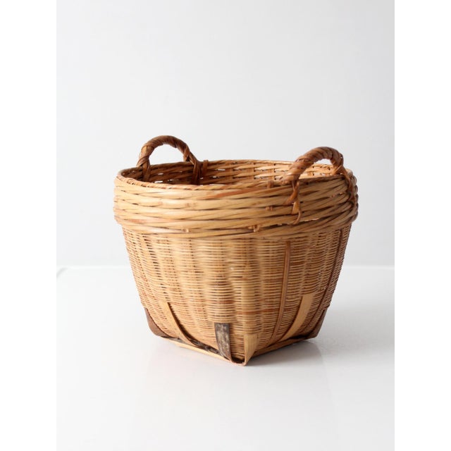 A vintage French Country style woven basket with a rounded form, wrapped side handles, bentwood reinforcing ribs, and...