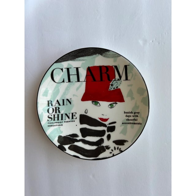 One plate has a woman with red hat, and various sayings "rain or shine", "foolproof fashion essentials." The other is a...